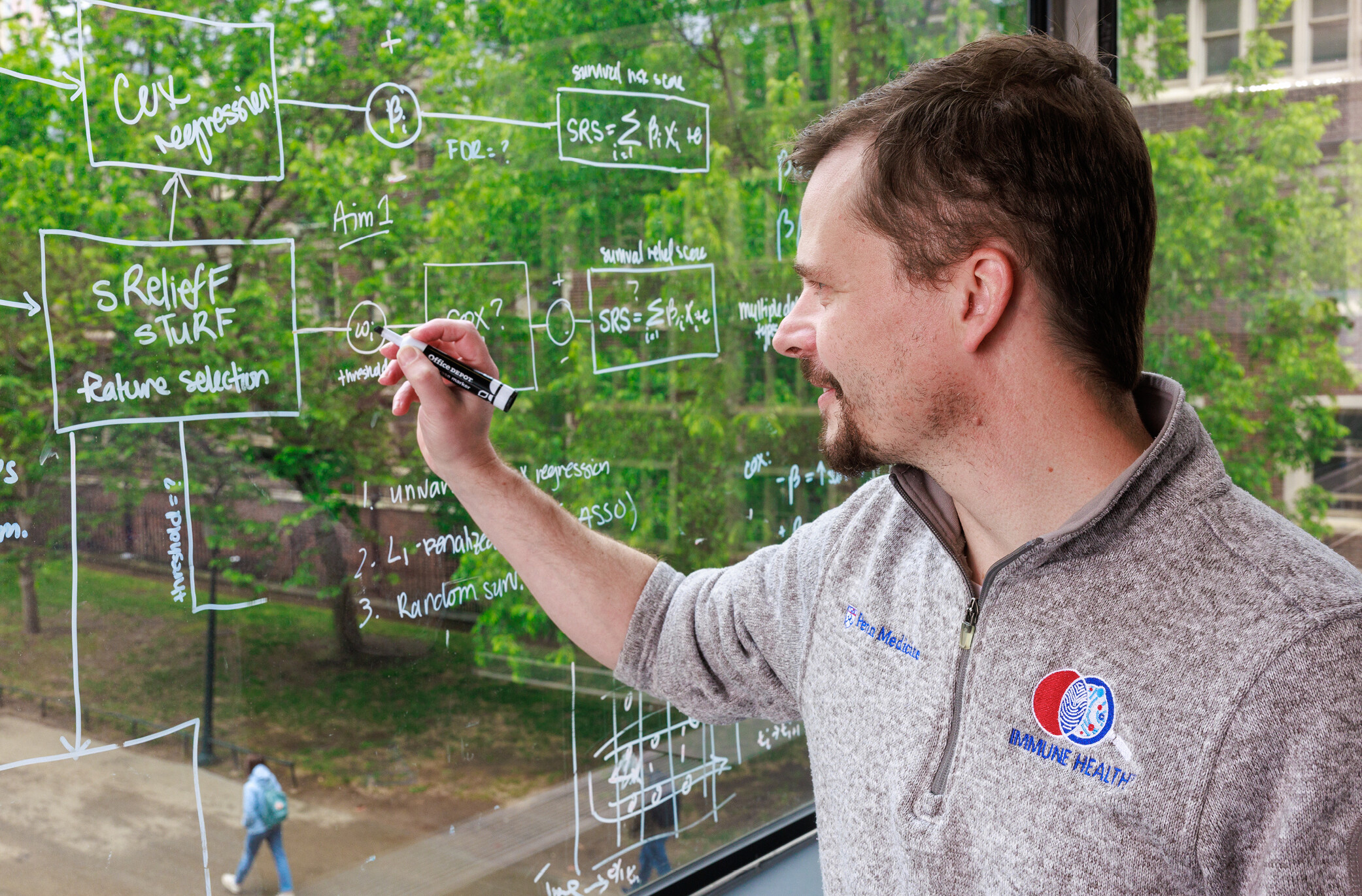 A person writing on a window overlooking Penn’s campus.