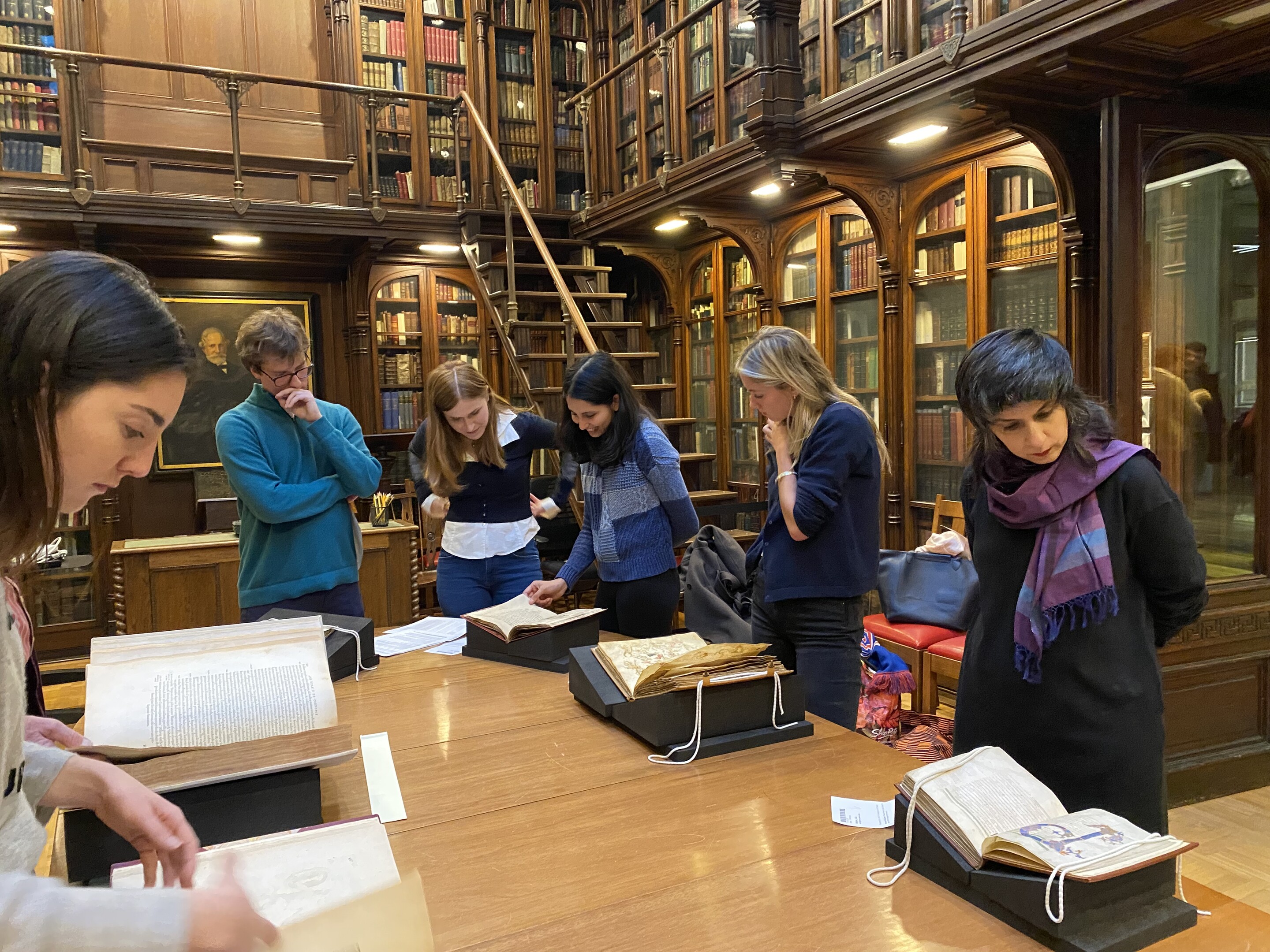 People lookiing at books on a table in a historic library. 