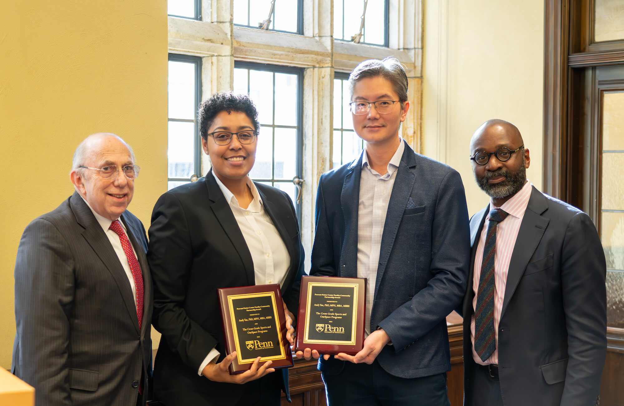 Ira Harkavy, Paulette Branson, Andy Tan, and John L. Jackson Jr. pose together at an award ceremony. Branson and Tan both hold plaques.