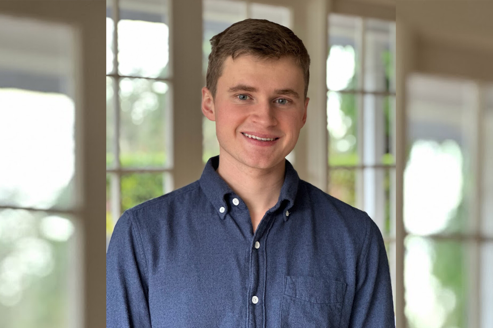 Xander Uyttendaele standing in front of a windowed door with sunlight streaming through