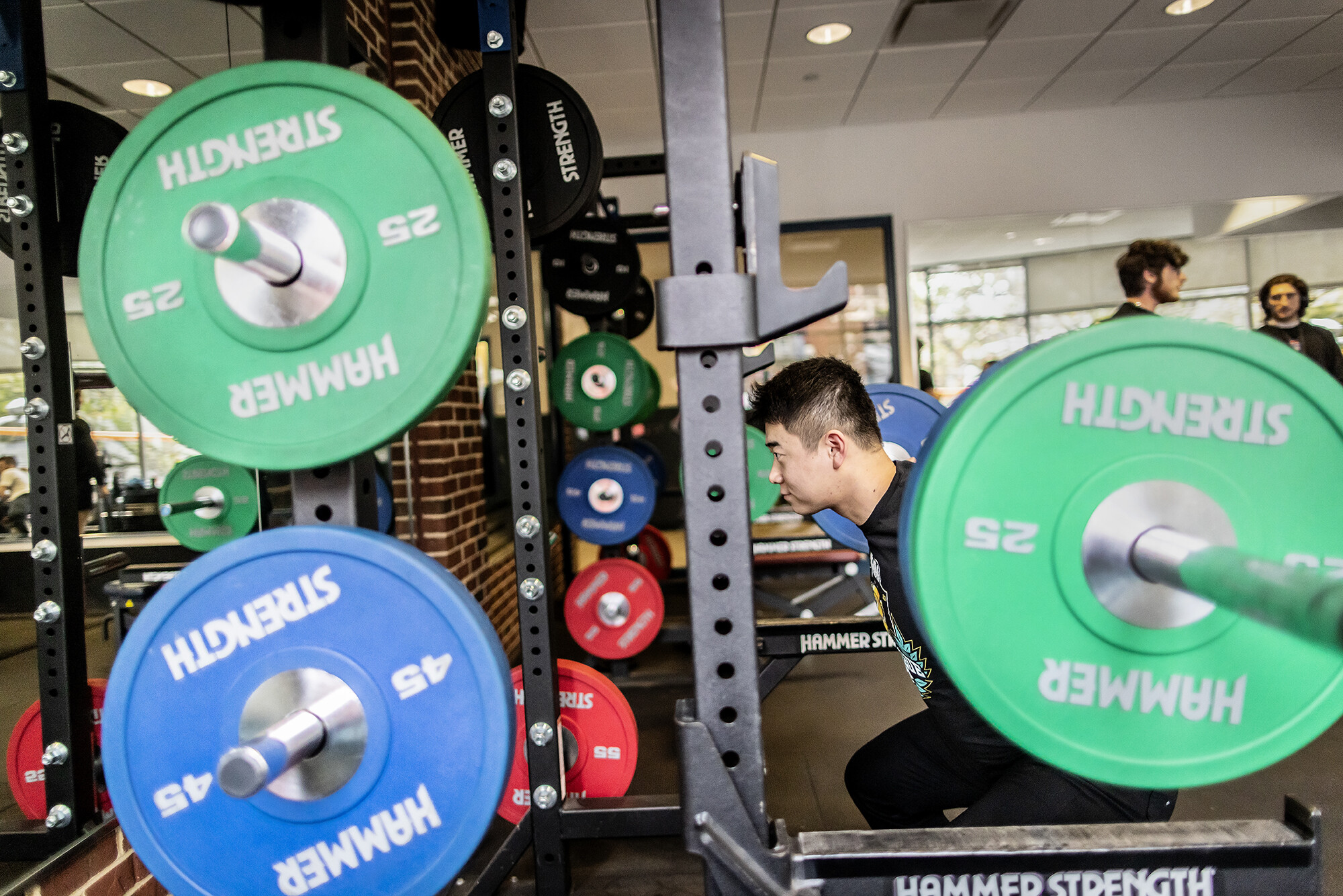 Student Hao Yu performs a barbell squat near the Smith machine.