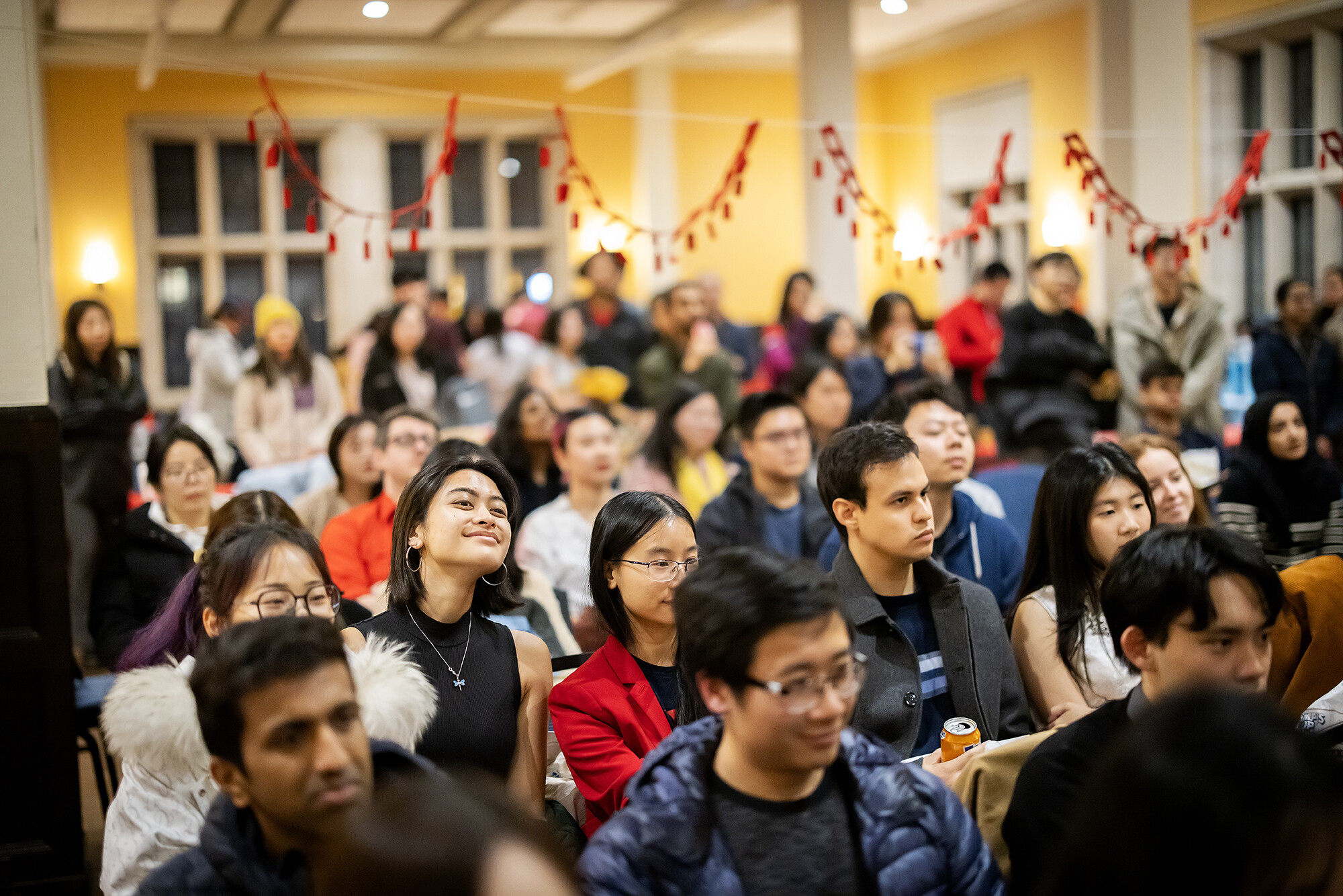 A crowd of people watching the Lunar New Year performances in Bodek. Red streamers are hung as decoration