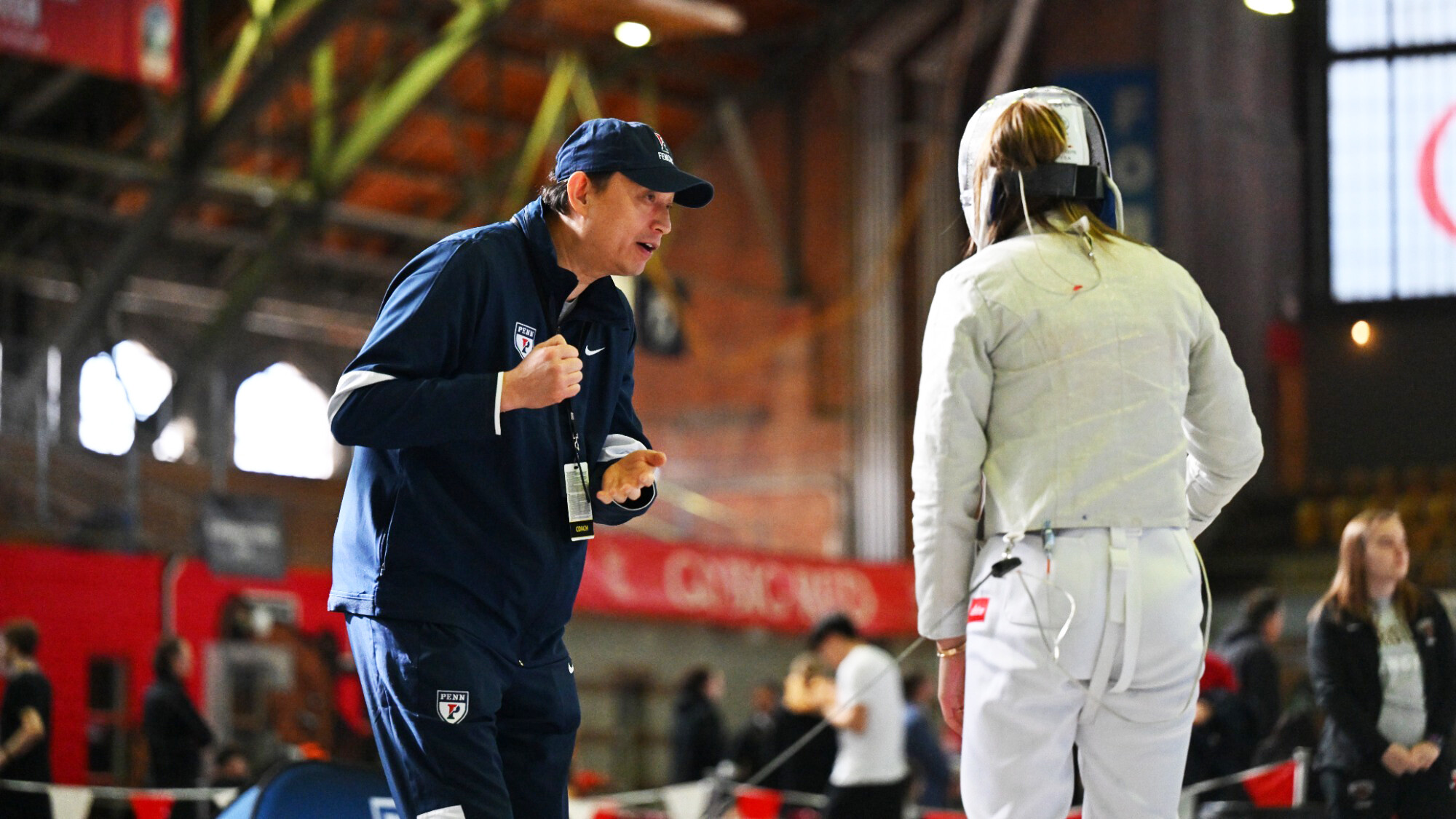 Andy Ma speaks with a fencer during a meet.