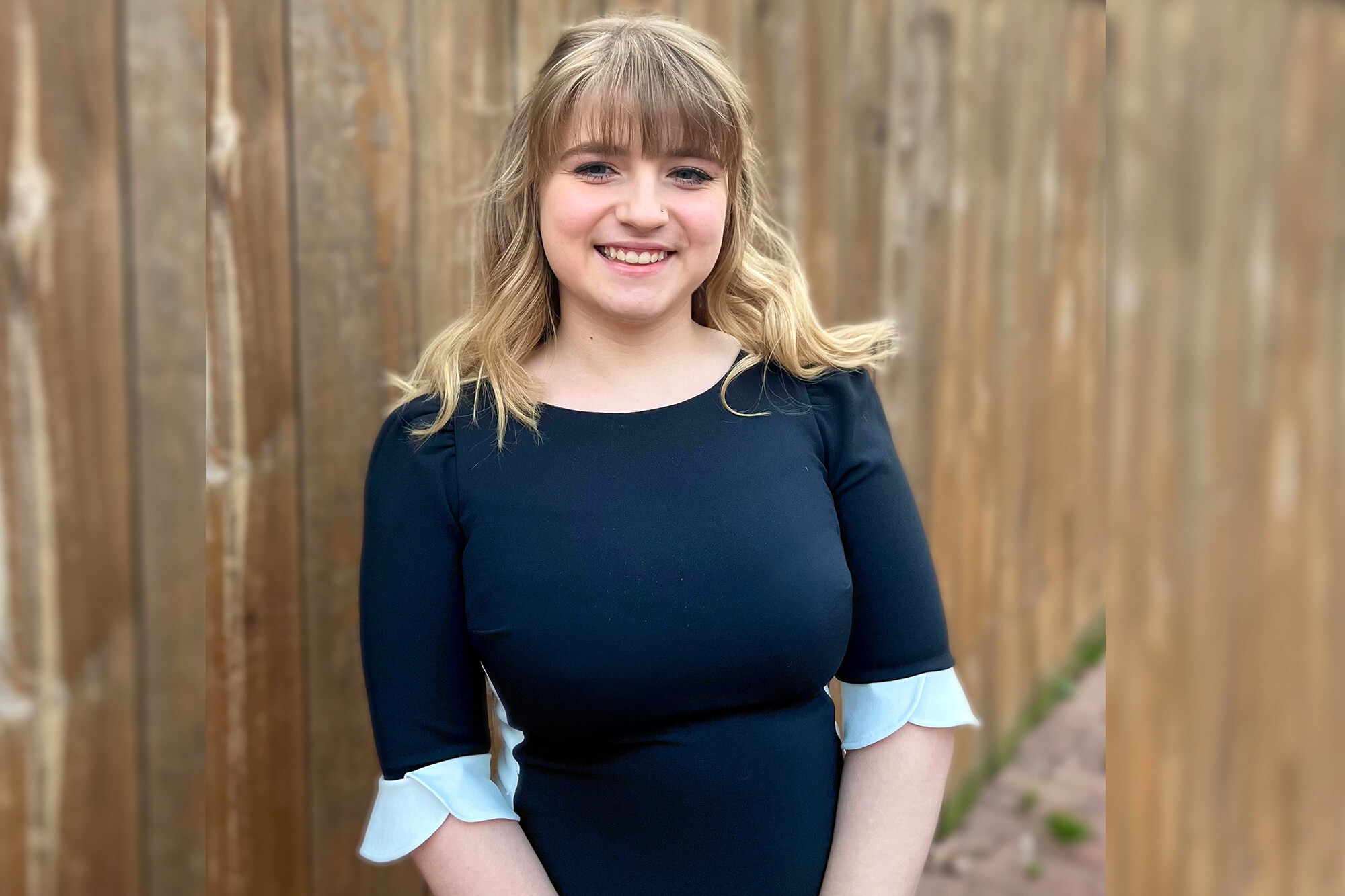Jade Golzalez standing outside with a wooden fence behind her
