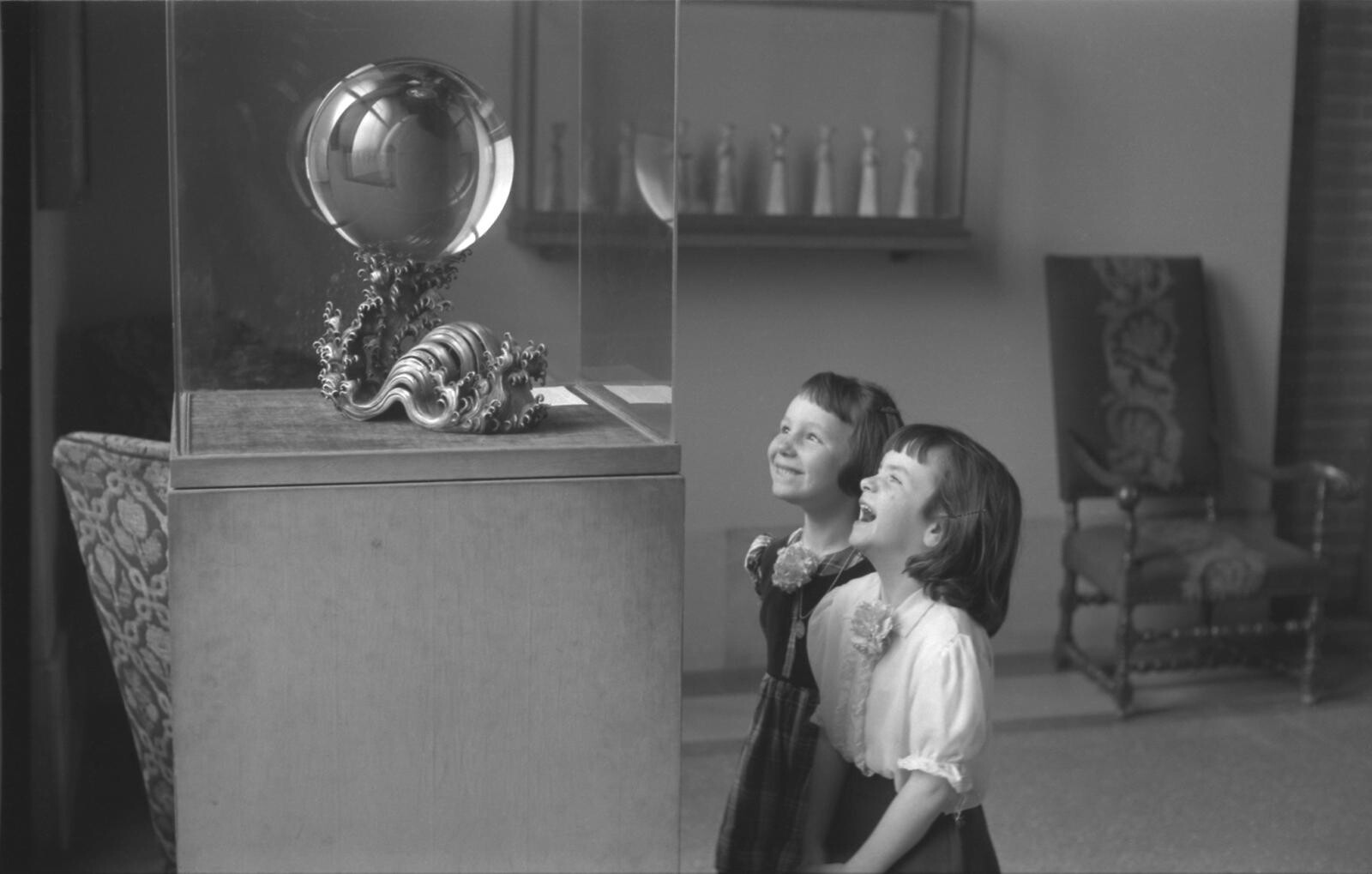 A historic, black-and-white image of two children gazing at the crystal ball 