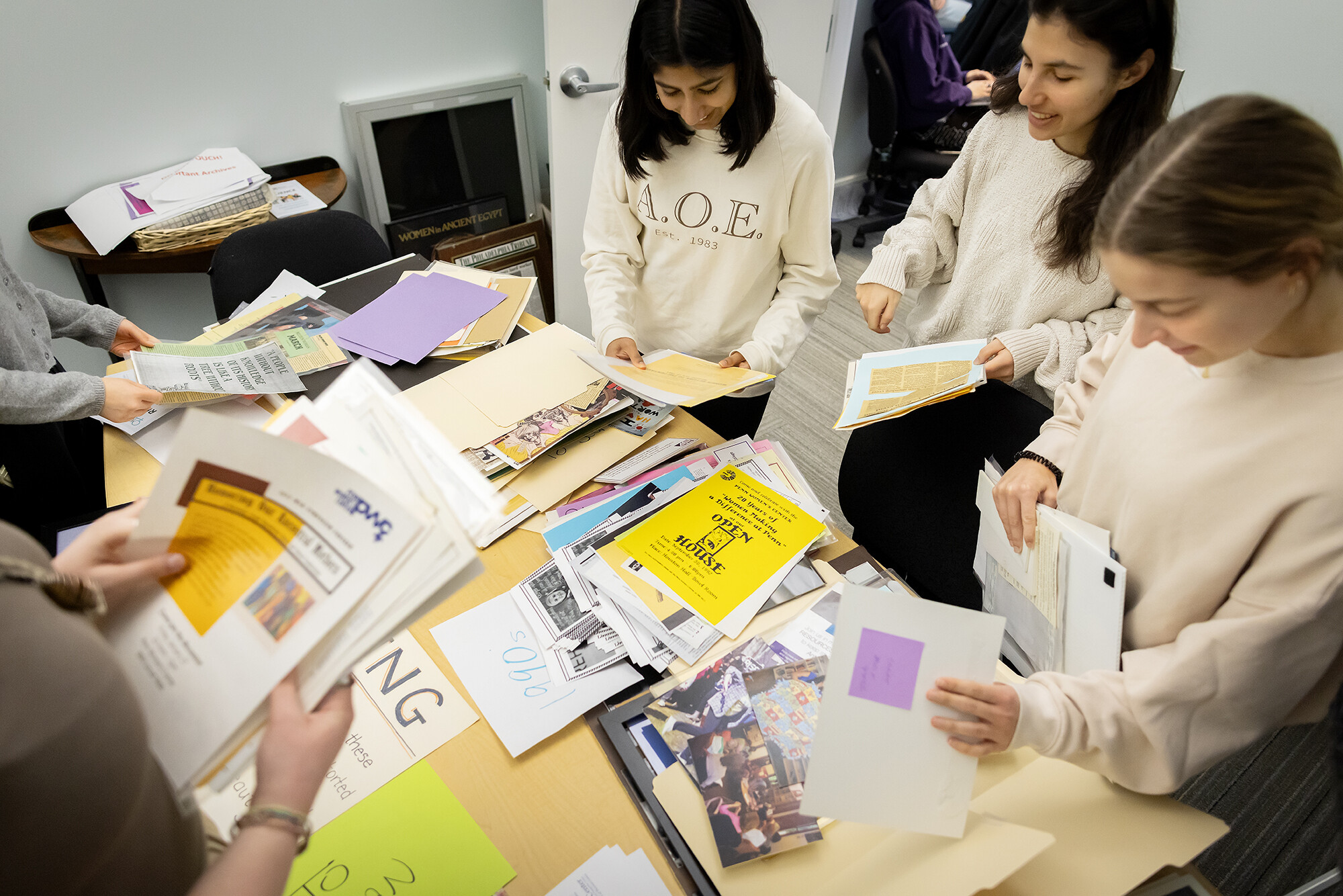 Five students looking at gender, sexuality, and women’s studies archival material.
