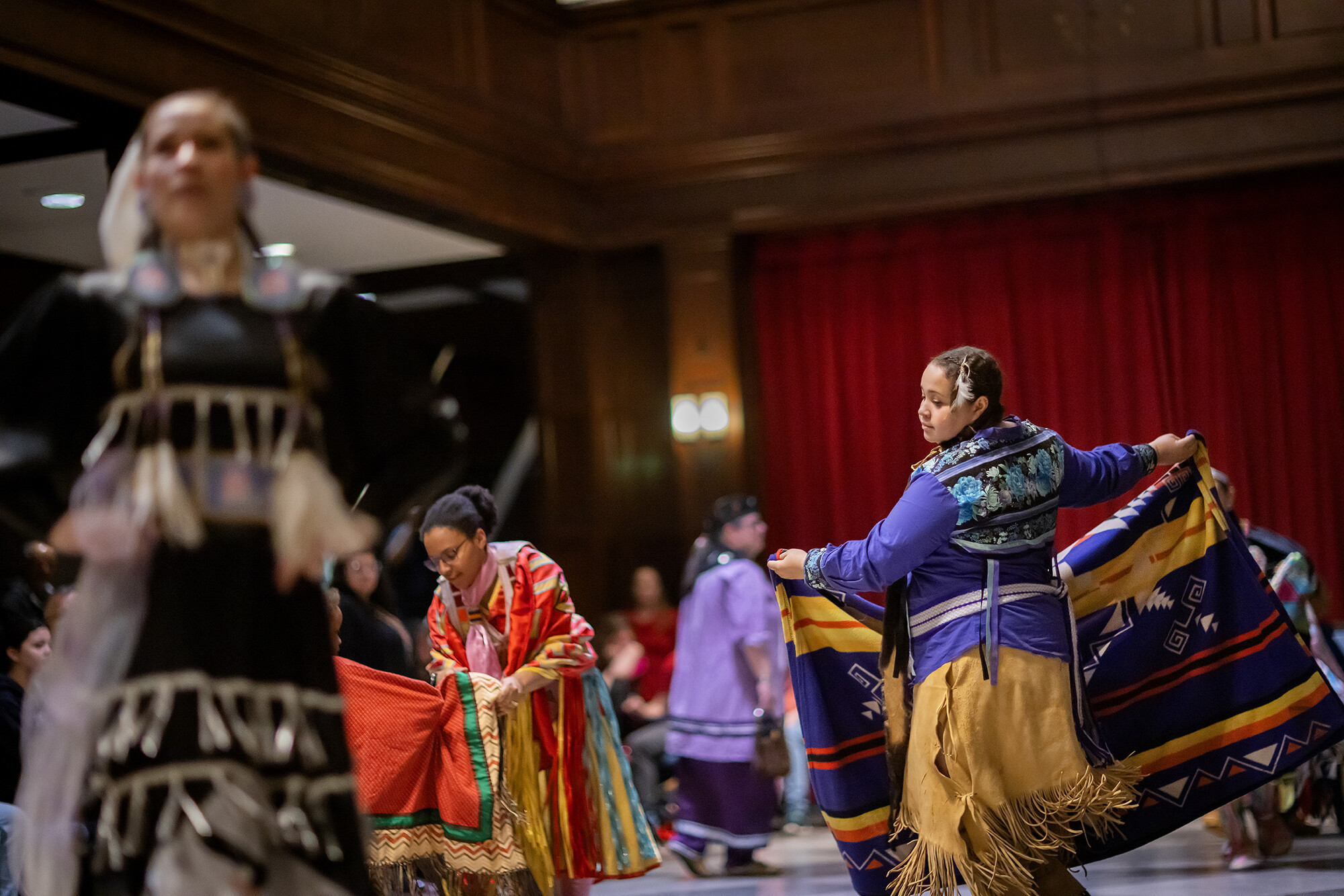 Keturah Peters, wearing a buckskin skirt and a purple top, performs a dance with a woven blanket