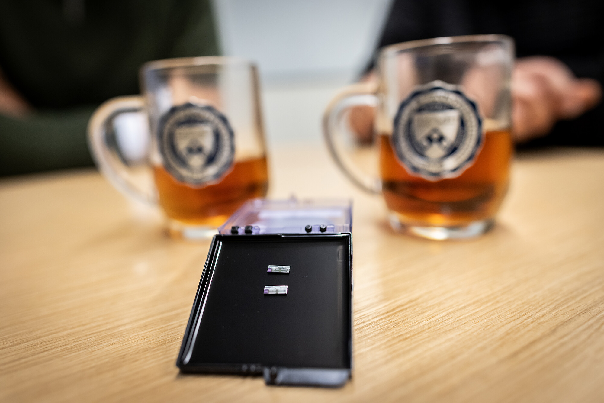 Computer chips resting on a plastic surface in front of two mugs filled with tea.