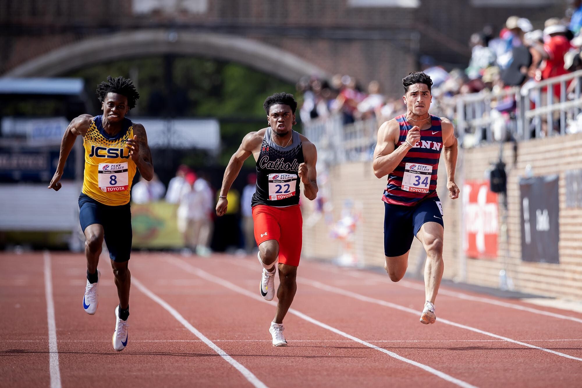 Runners running on the track at Franklin Field during the Penn Relays.