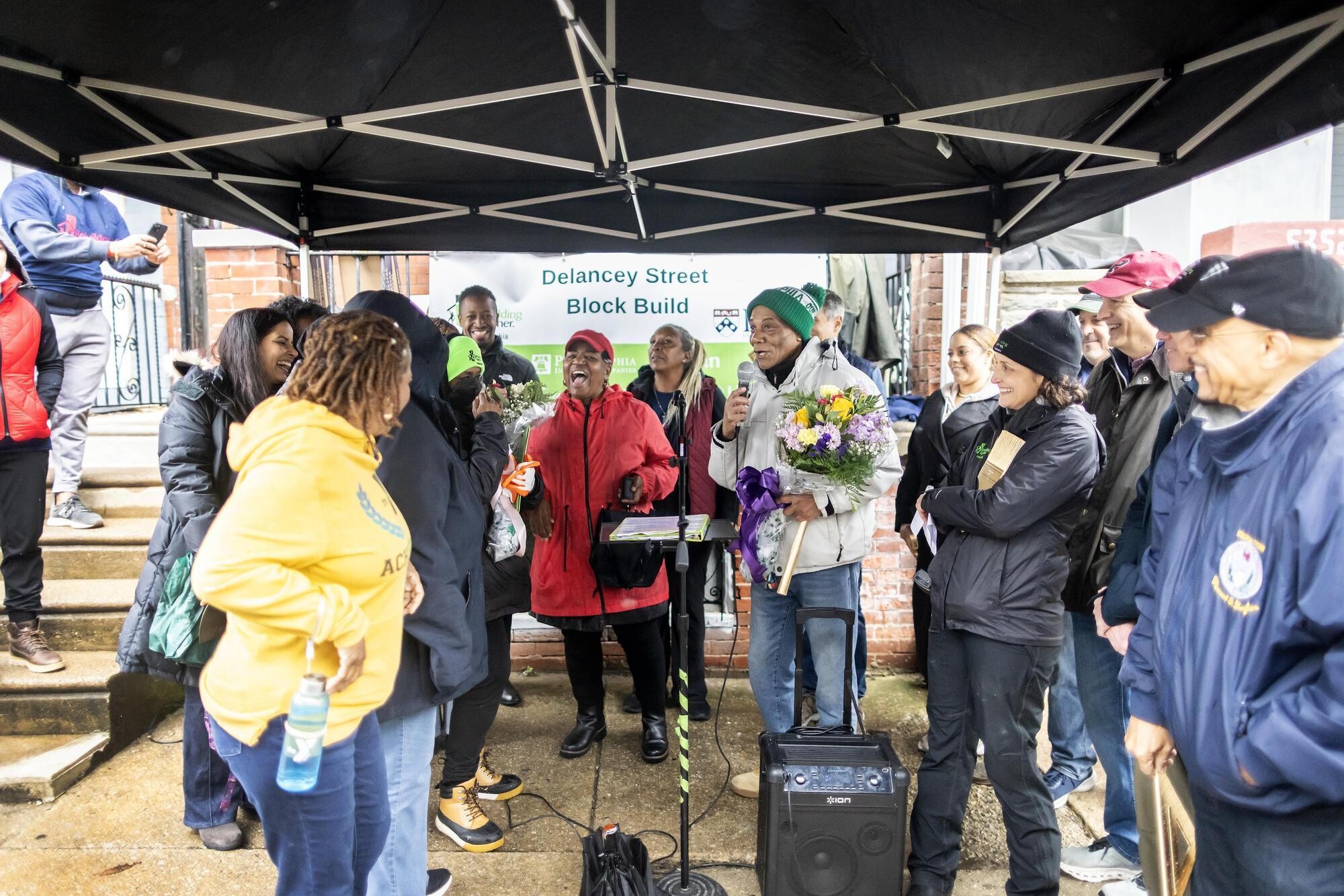 Local homeowner Rudy Edge speaking at the Rebuilding Together Philadelphia block build as listeners smile and cheer.