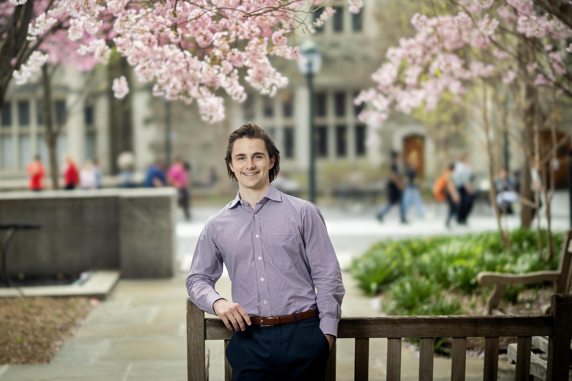 William Reason standing outside with cherry blossom trees behind.
