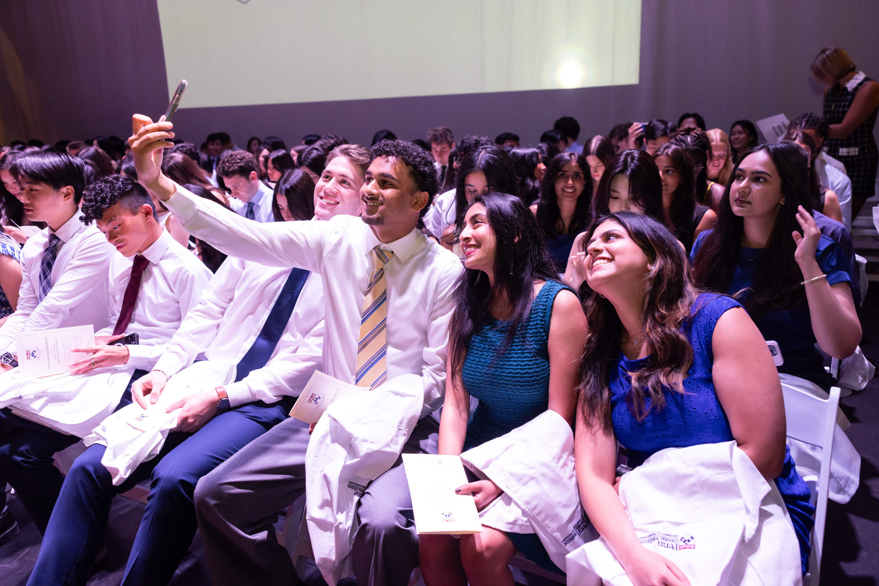 Dental students taking selfies at the Penn Dental white coat ceremony.