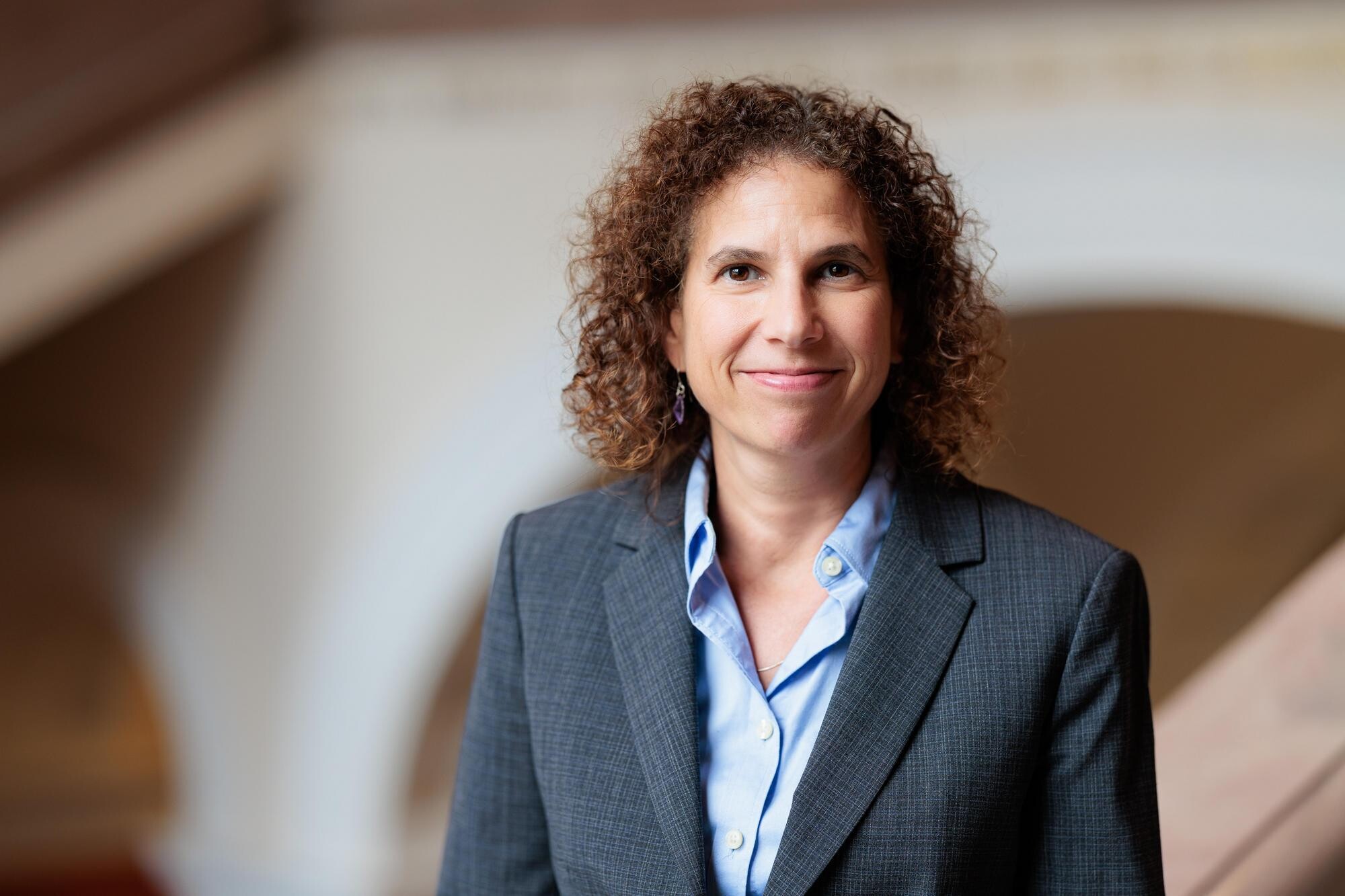 Jennifer Rothman stands in front of a brown and white wall.