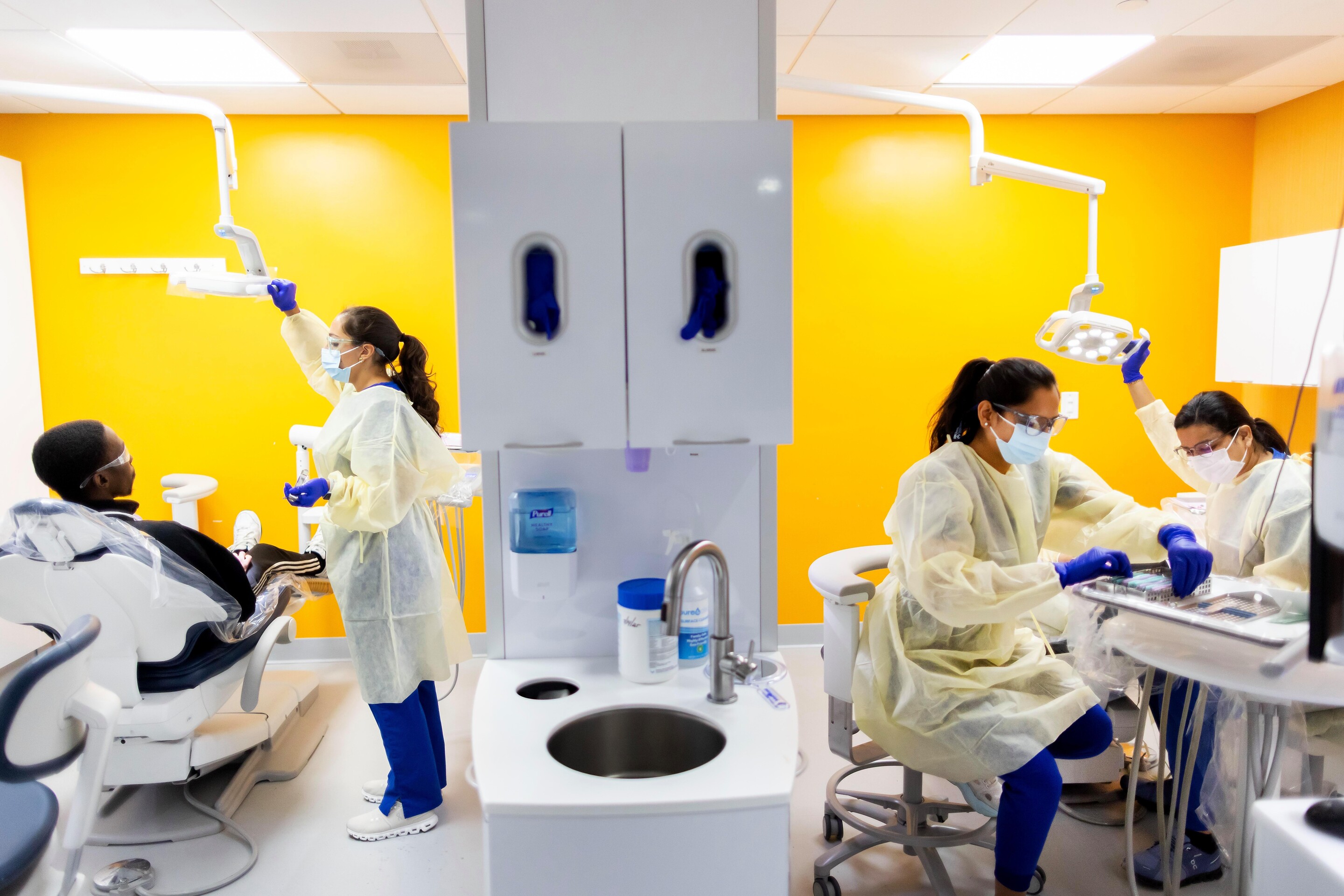 3 Penn Dental Medicine students at the Cedar location in the clinic with a patient.