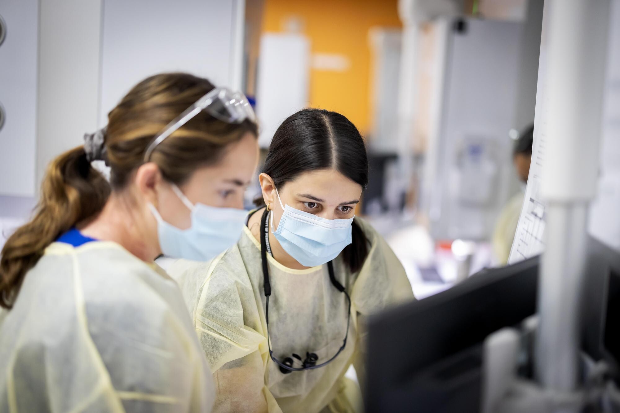 Two Penn Dental students looking at a computer screen in the clinic.
