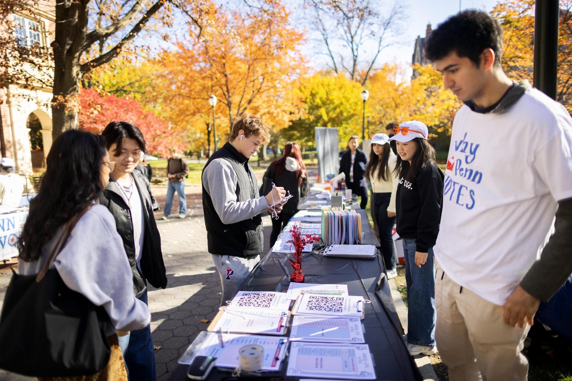 Volunteers with Penn Leads the Vote talk with students at tables set up outside on Locust Walk.