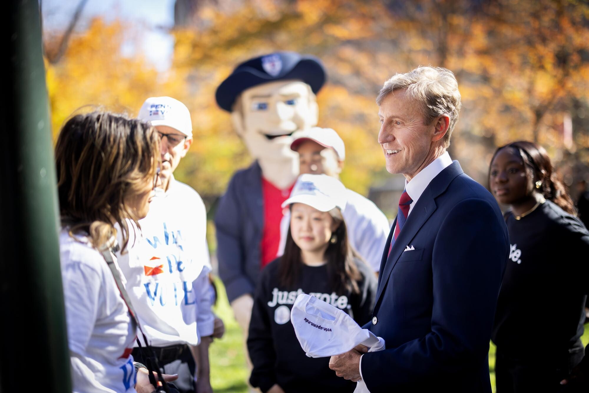 Penn President J. Larry Jameson talking with volunteers with Penn Leads the Vote with the Quaker mascot.