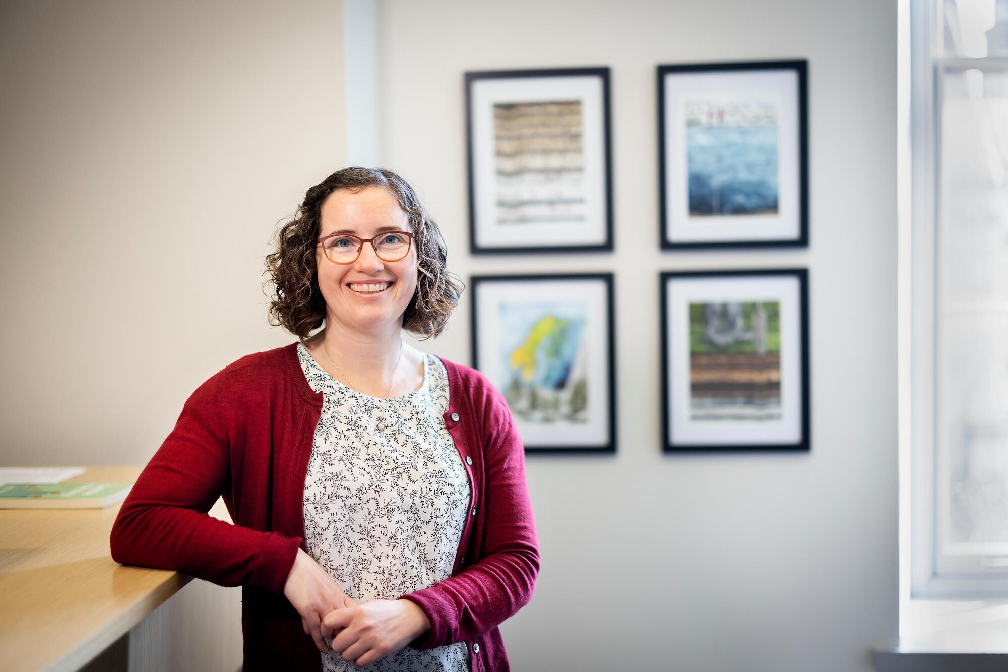 Melissa Charenko stands in front of art in her office.
