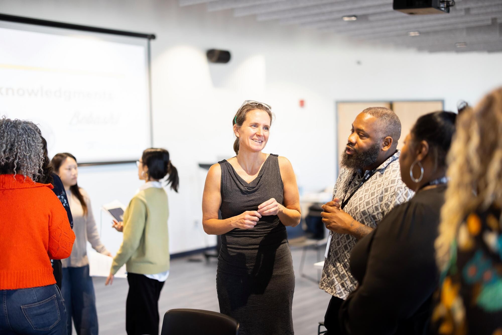 A professor speaking with people in a classroom.