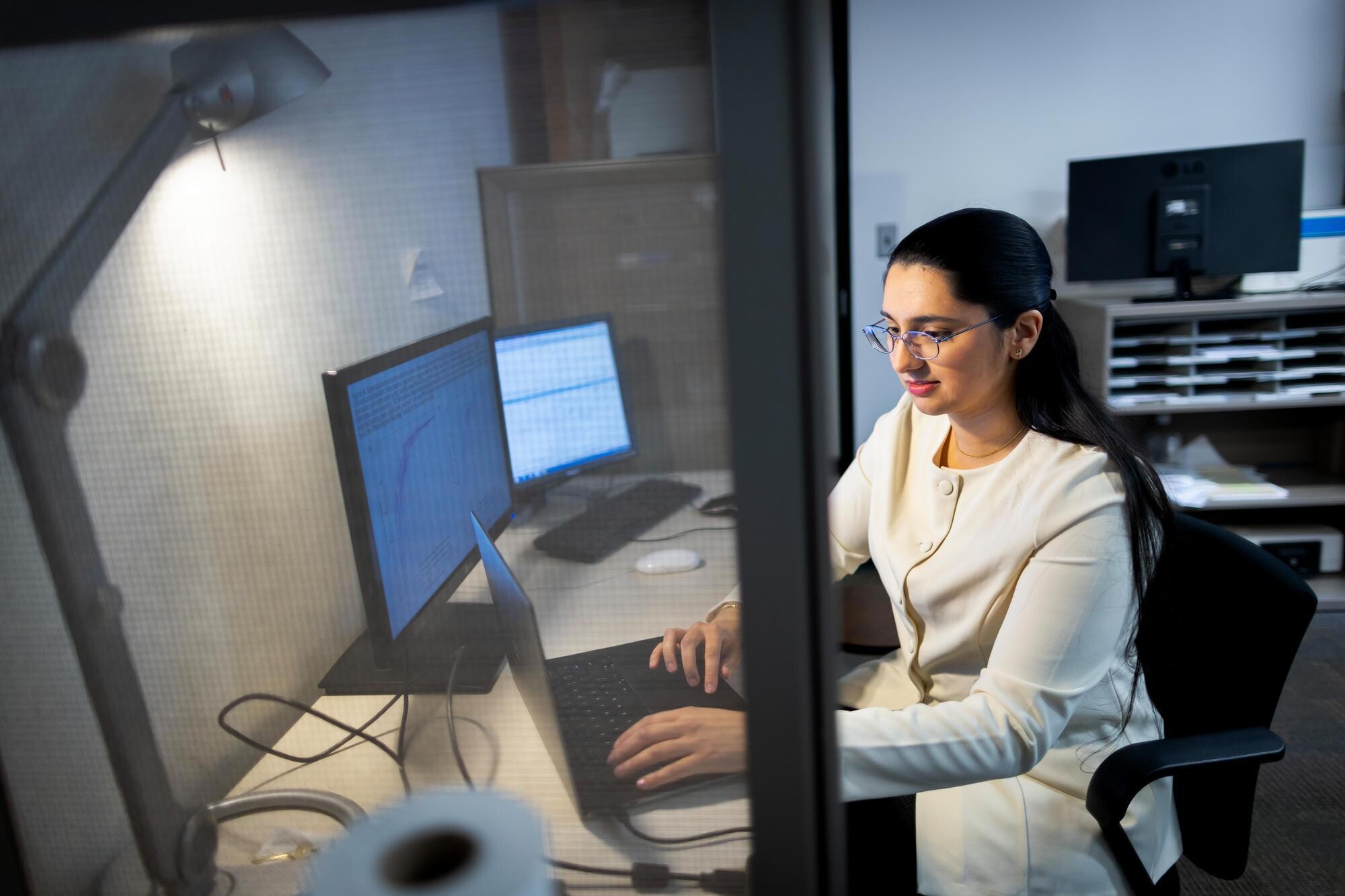 Shreya Parchure seated at a computer looking at research data and brain scan imaging in the Laboratory for Cognition and Neural Stimulation in the Goddard Laboratory.