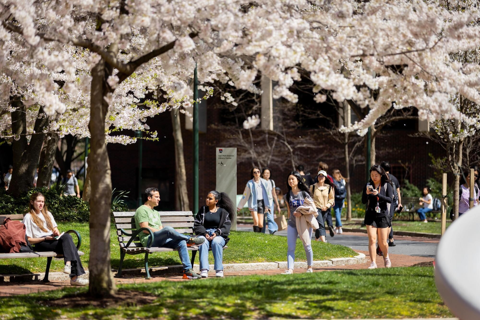 People walking and seated near the entrance to Van Pelt Library.