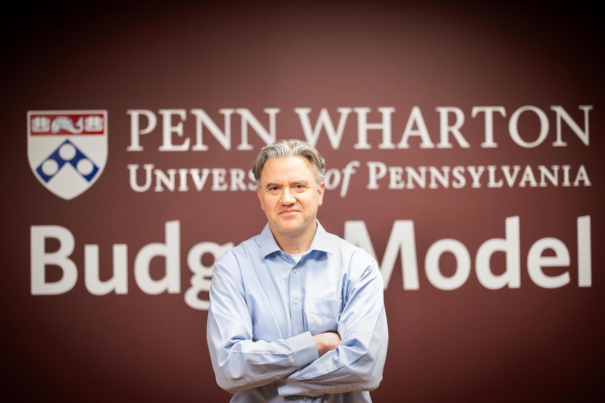 Kent Smetters in front of a sign that reads Penn Wharton Budget Model.