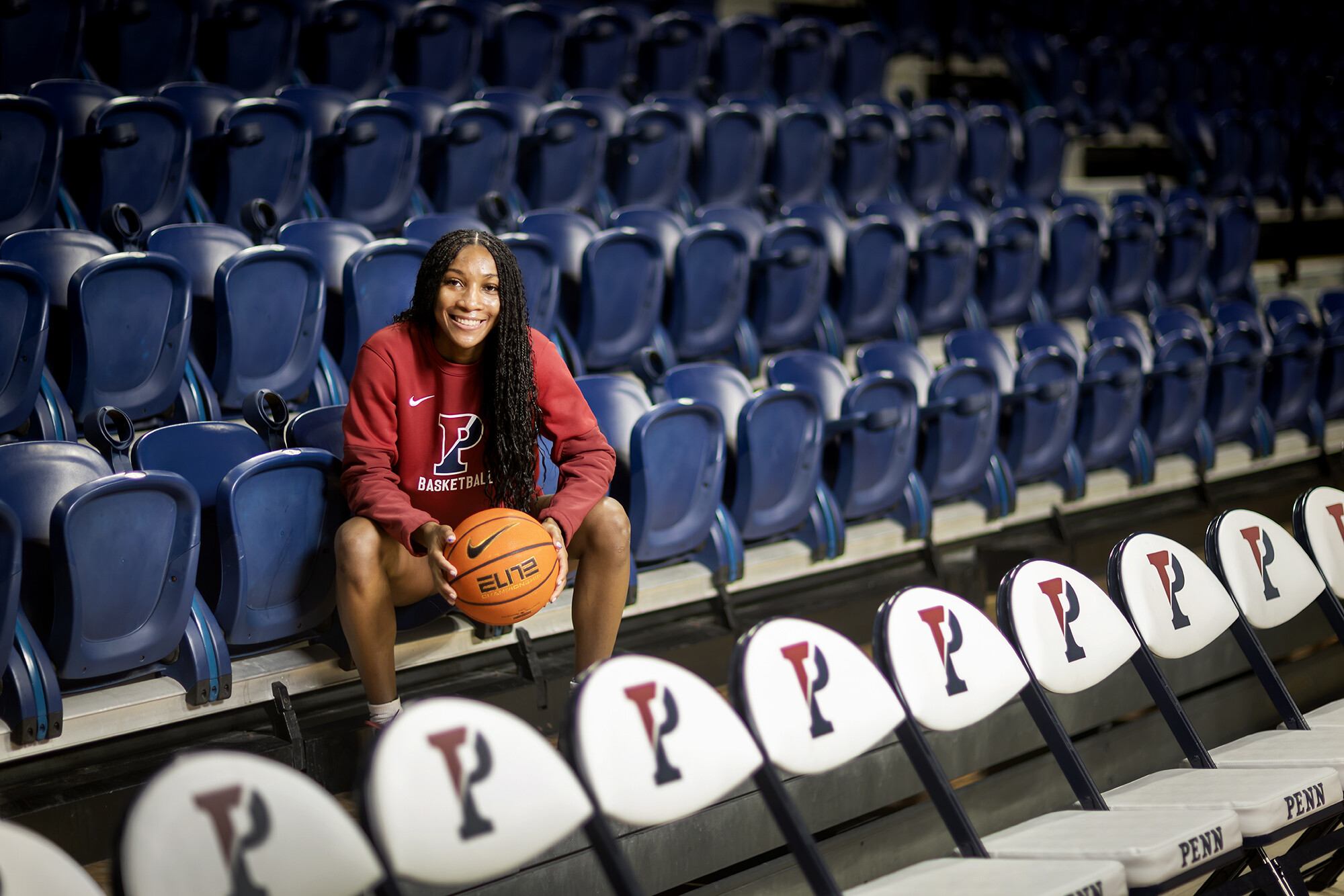 Simone Sawyer holds a basketball while seating in the bleachers at the Palestra.