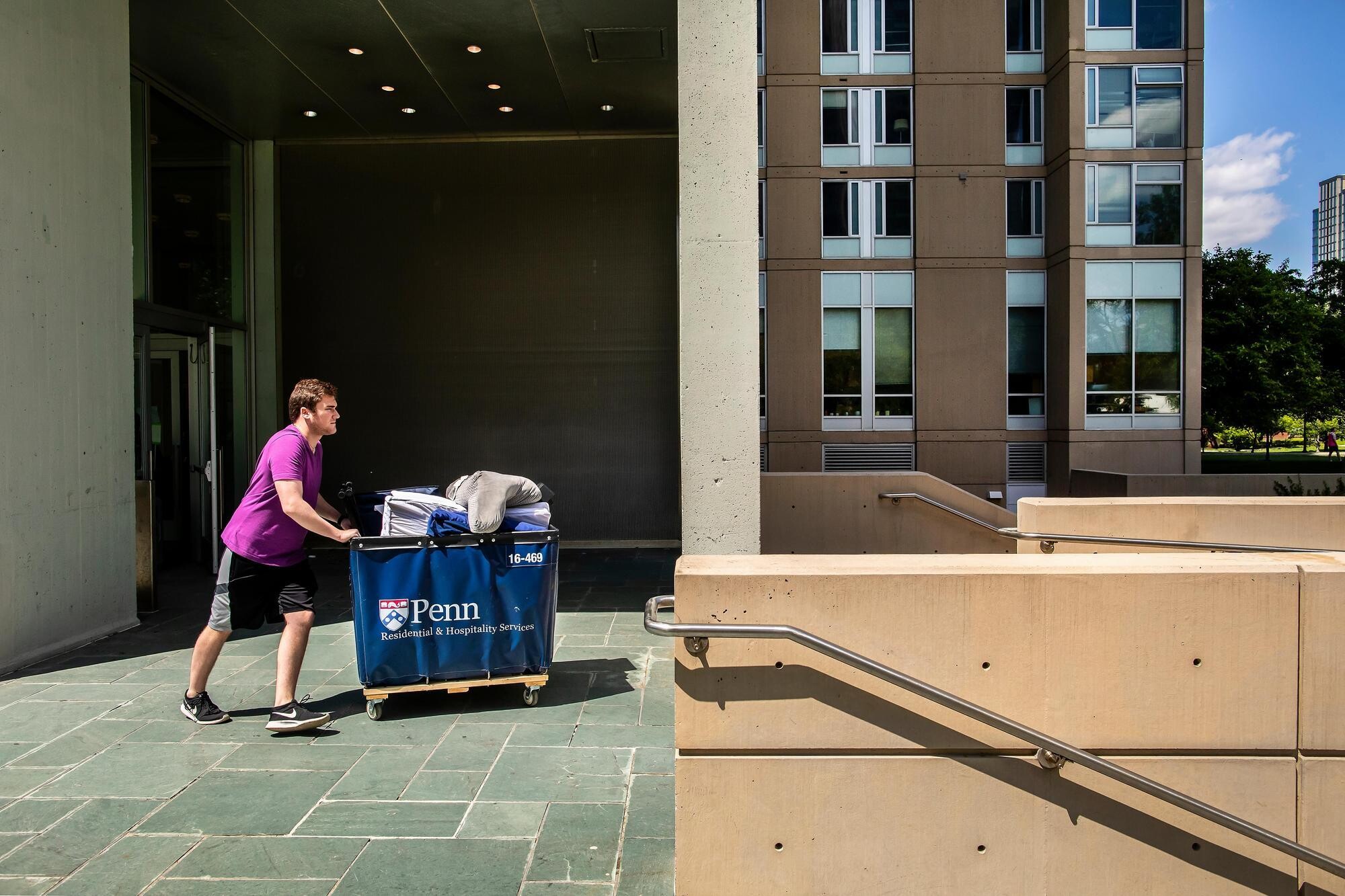A student pushing a Move-Out cart out of a dorm on Penn’s campus.