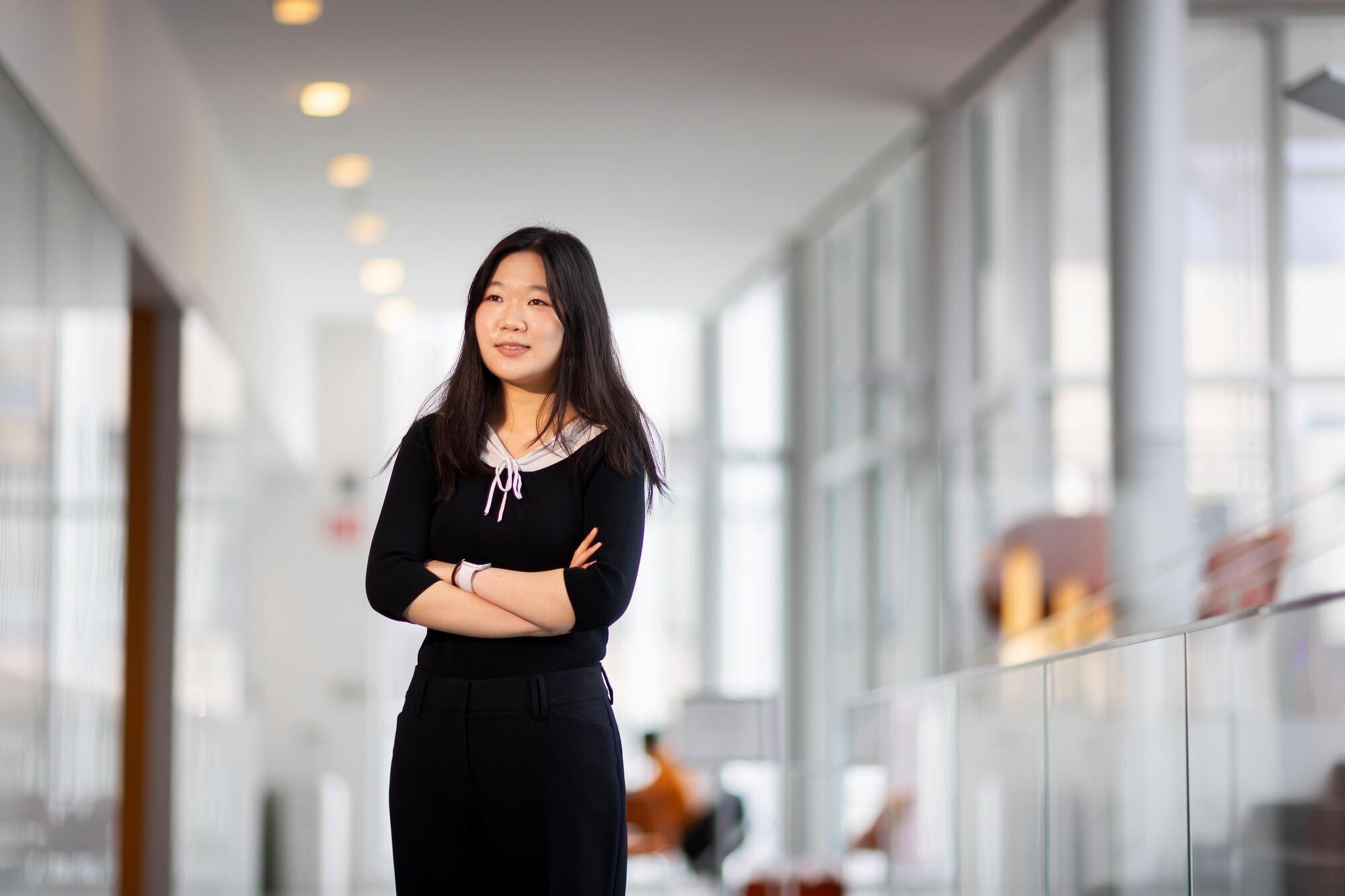 Caitlyn Chen posing for a photo, arms crossed, inside the lobby of the Singh Center for Nanotechnology.