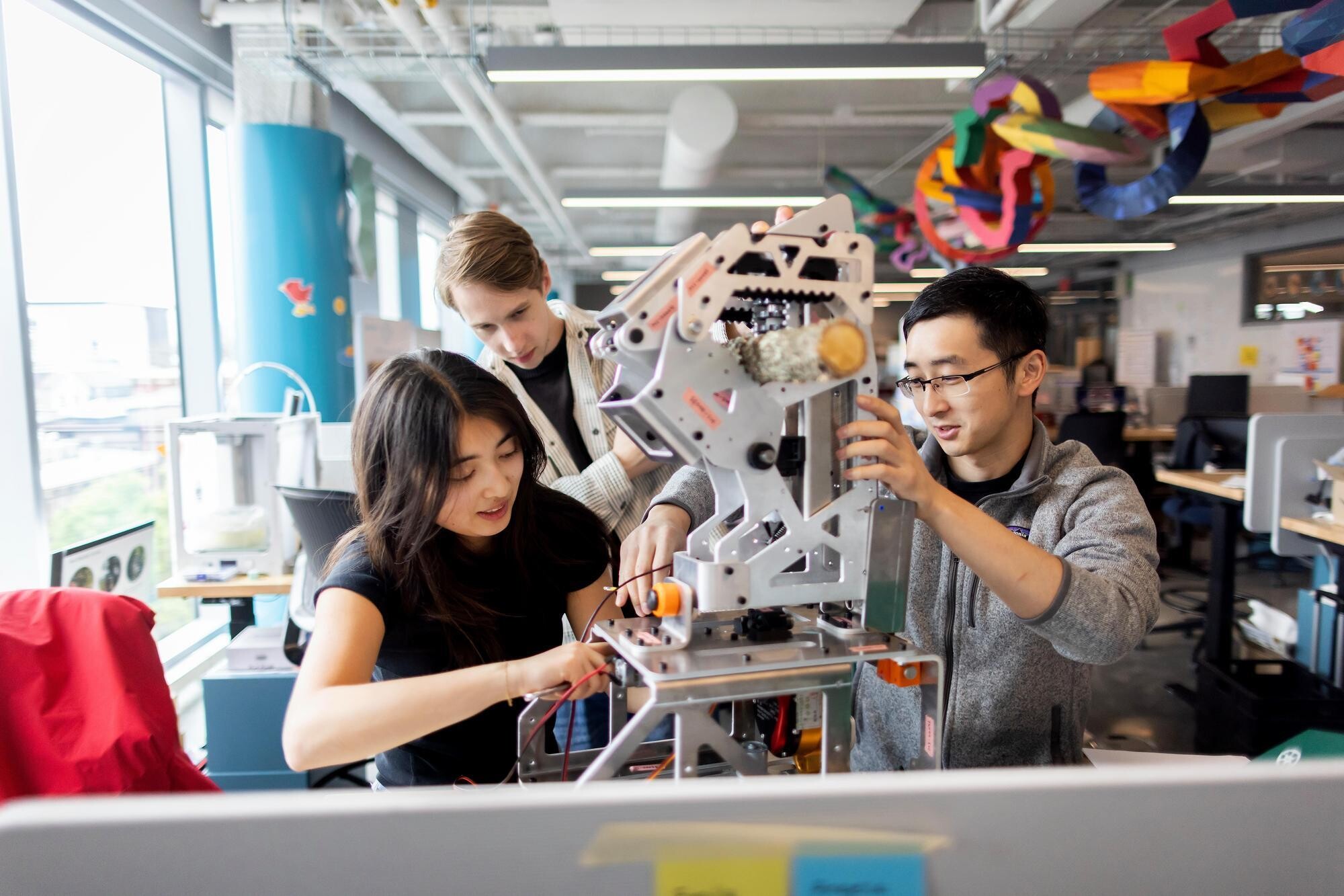 Margaret Zhu working on a robot with two team members in Tangen Hall.