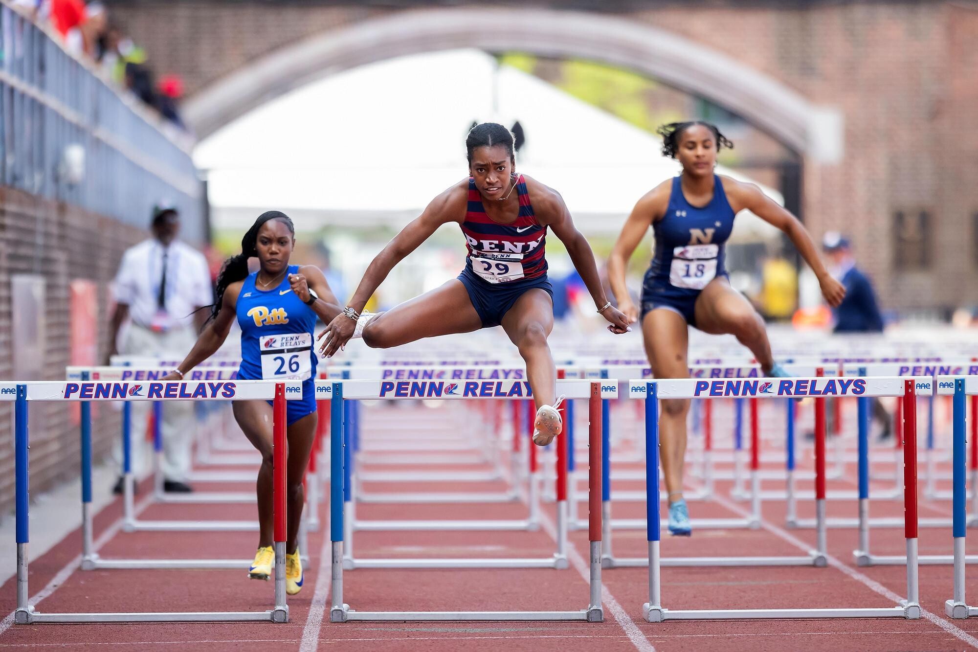 Runners jumping over the hurdles on Franklin Field during Penn Relays.