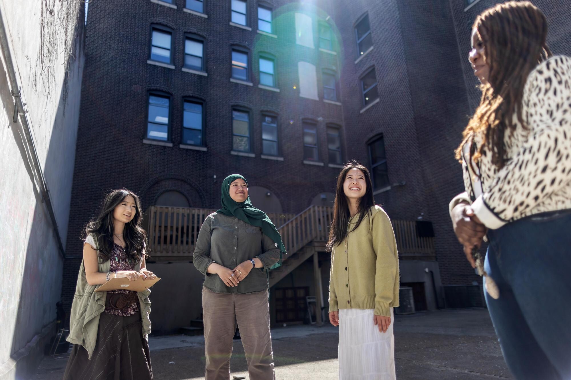 Four people in a courtyard smiling.