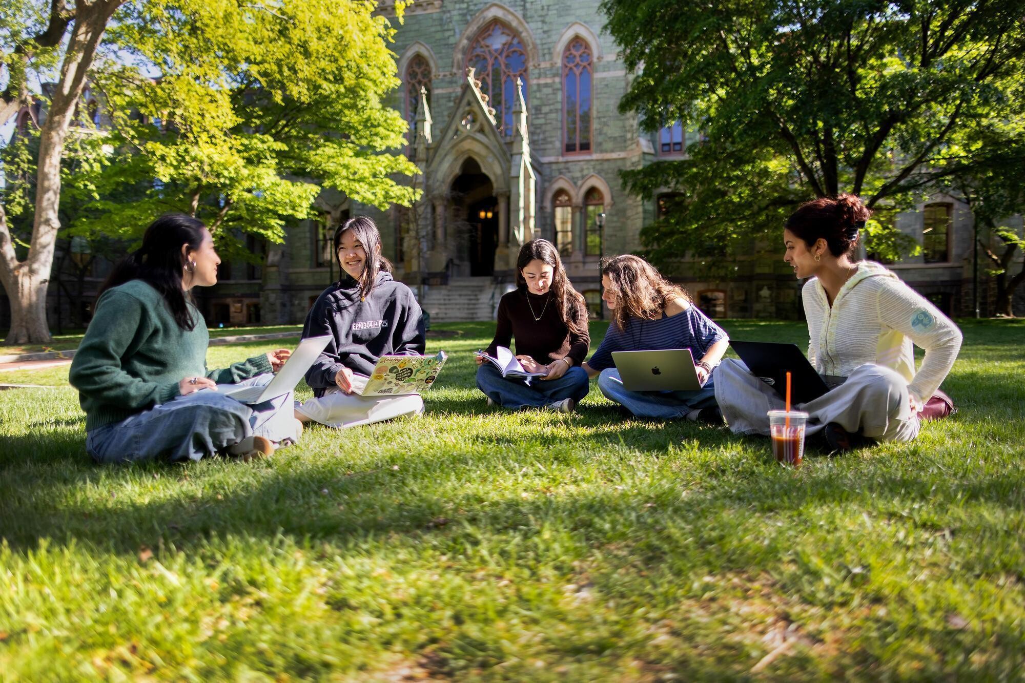 Penn students sitting on College Green in front of College Hall.