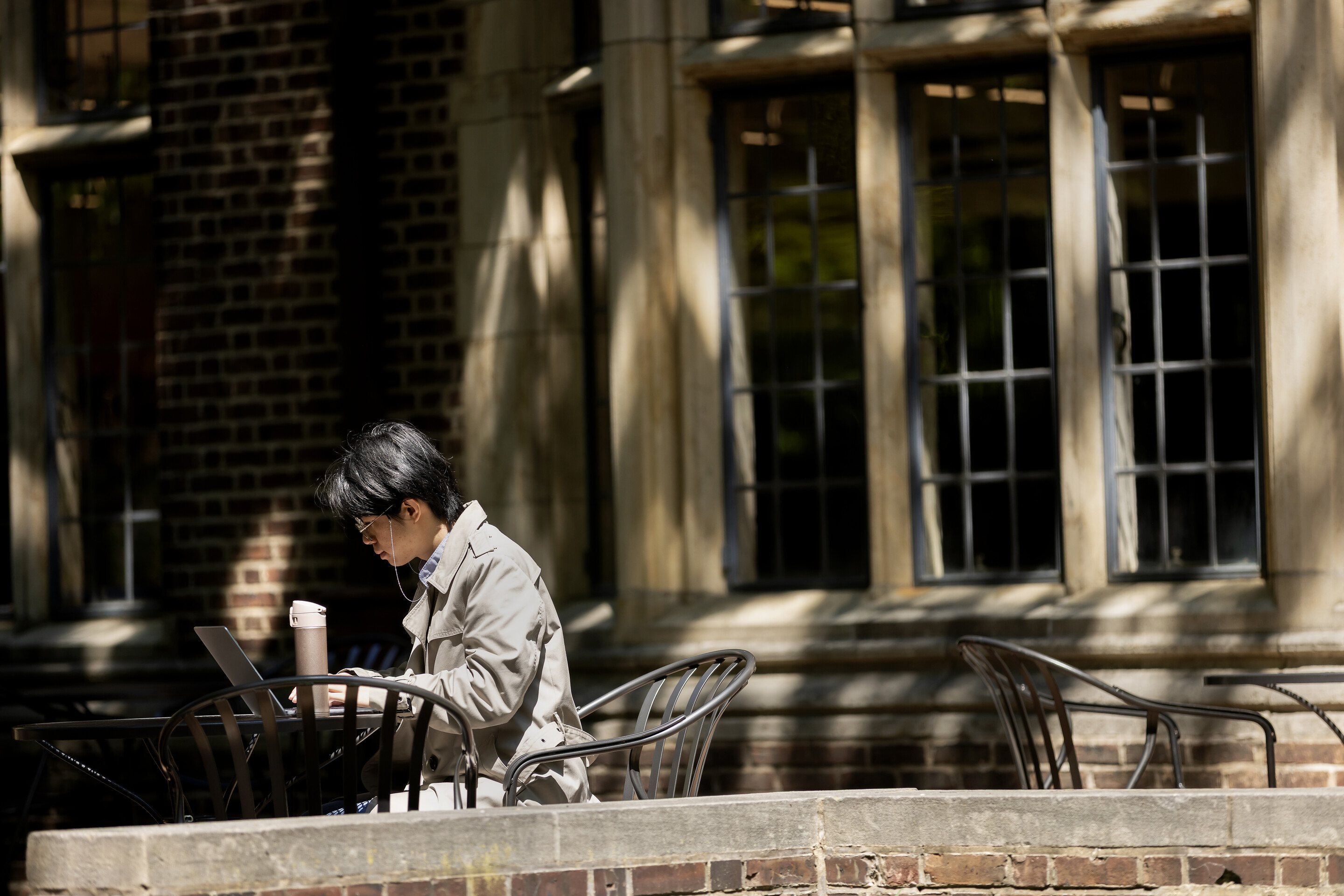 A person working on their laptop outside at a table during Reading Day.
