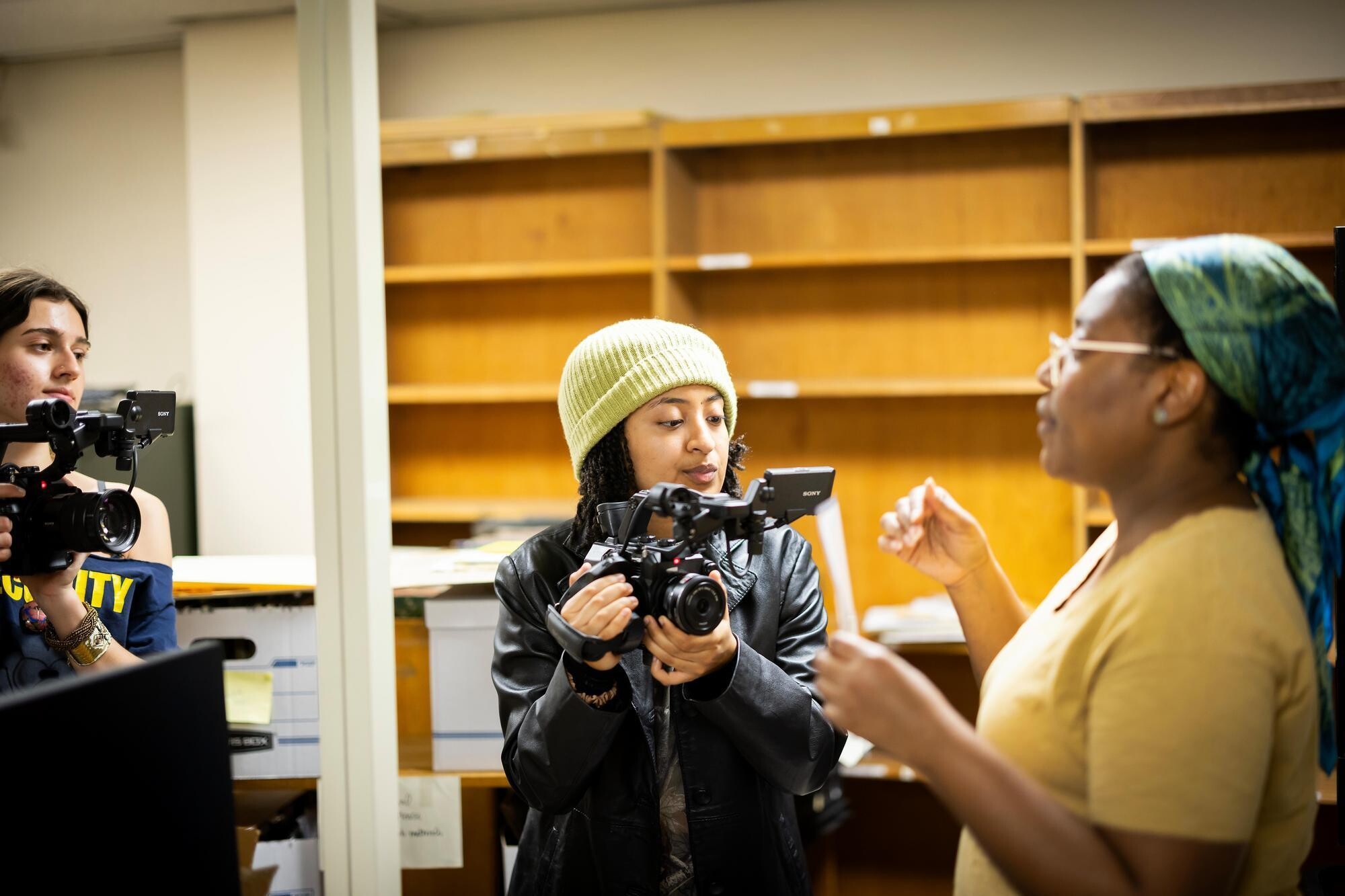 Two students take video of library archivist speaking.