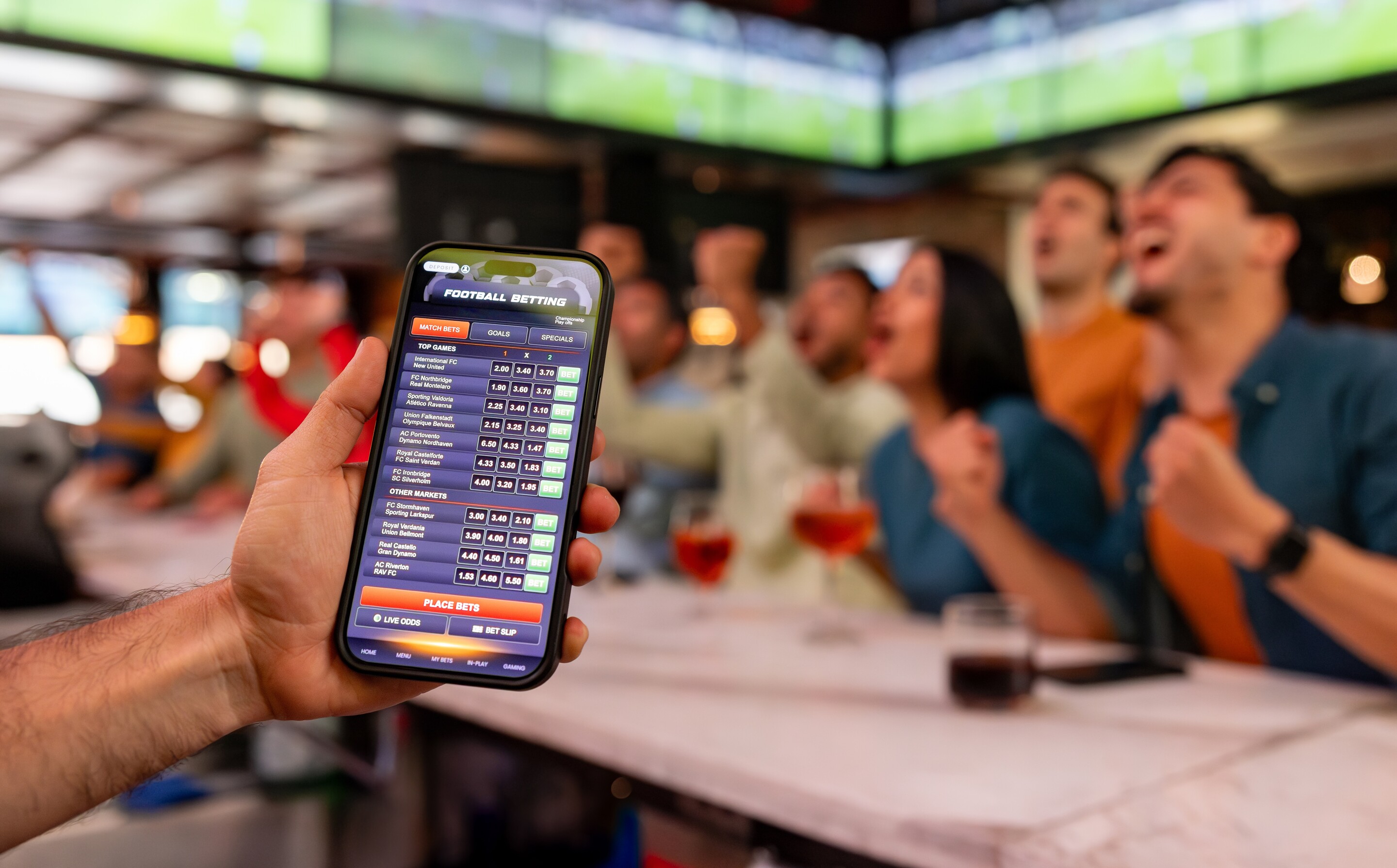 Hand holding a mobile phone with sports bets lined up.  