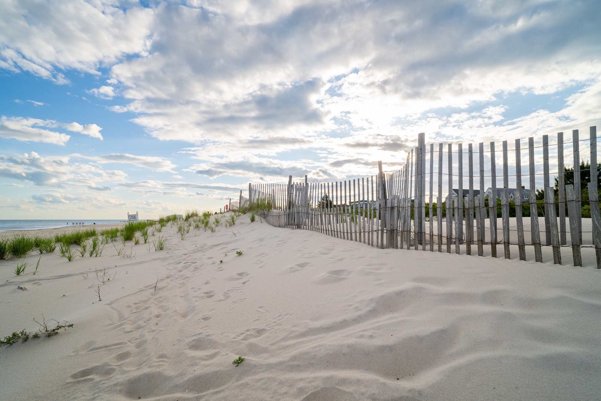 A wooden fence in the sand of a beach.