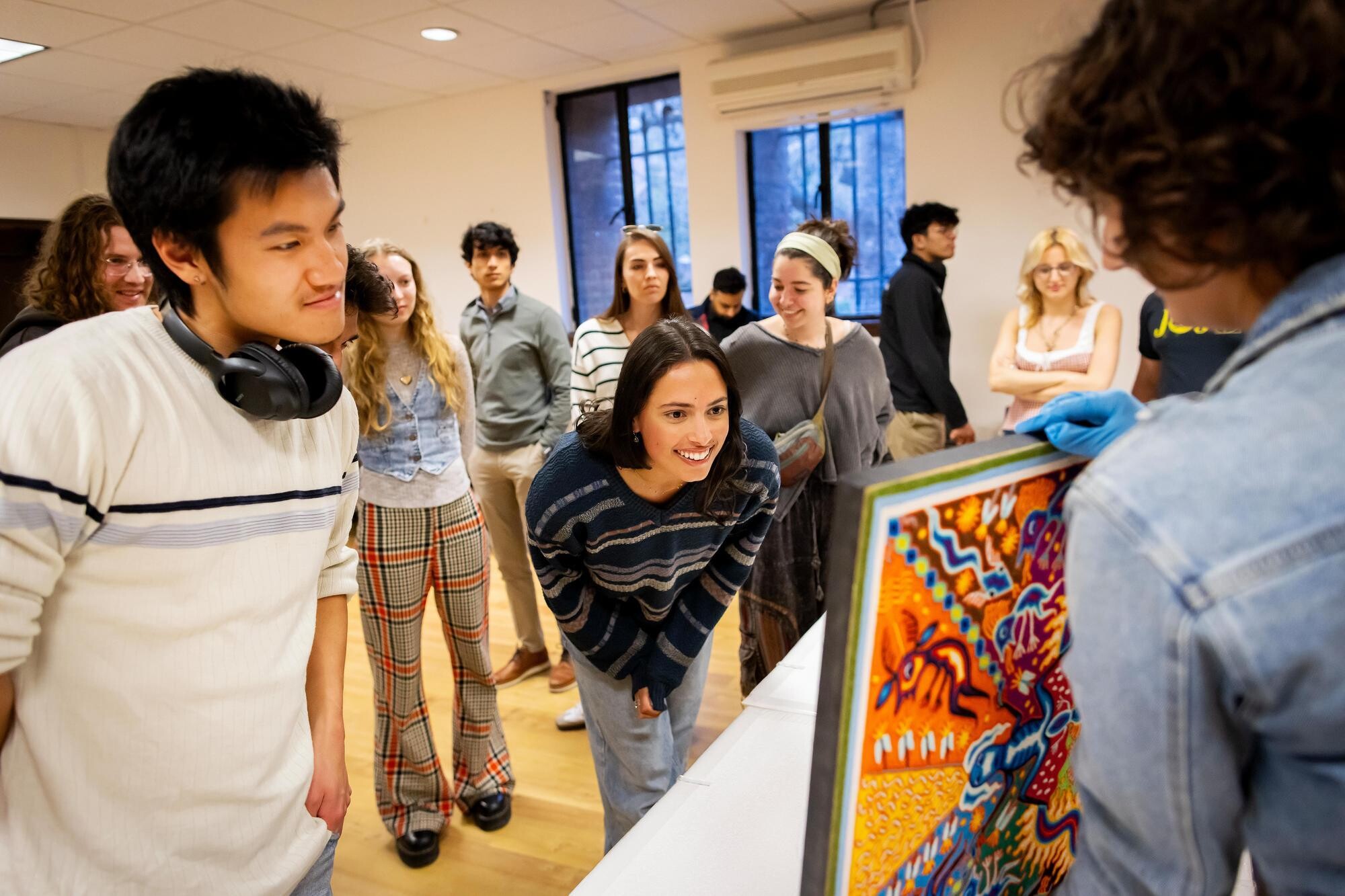 Students look at Huichol yarn painting at Penn Museum.