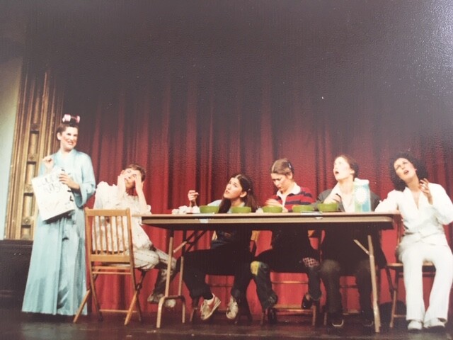 On-stage-six-performers-at-a-breakfast-table-set-with-cereal-bowls