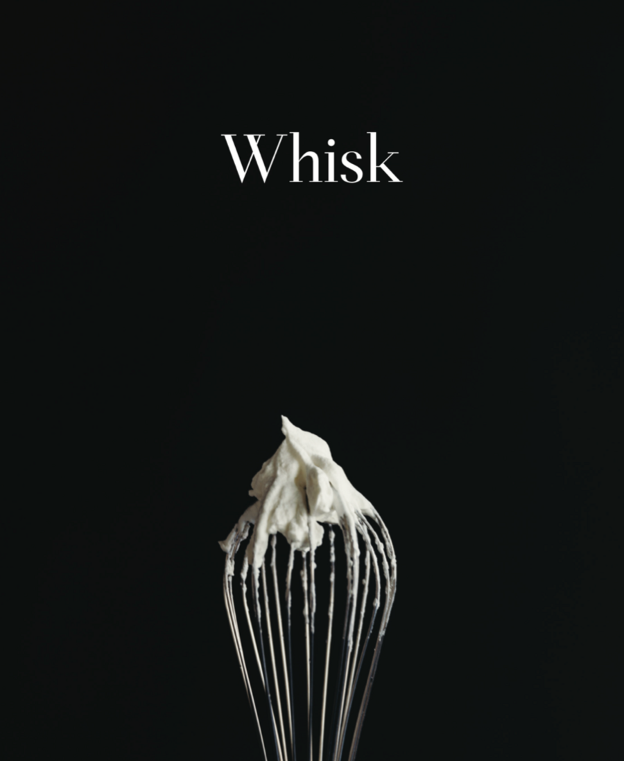 A whisk covered in a thick white batter in front of a black backdrop