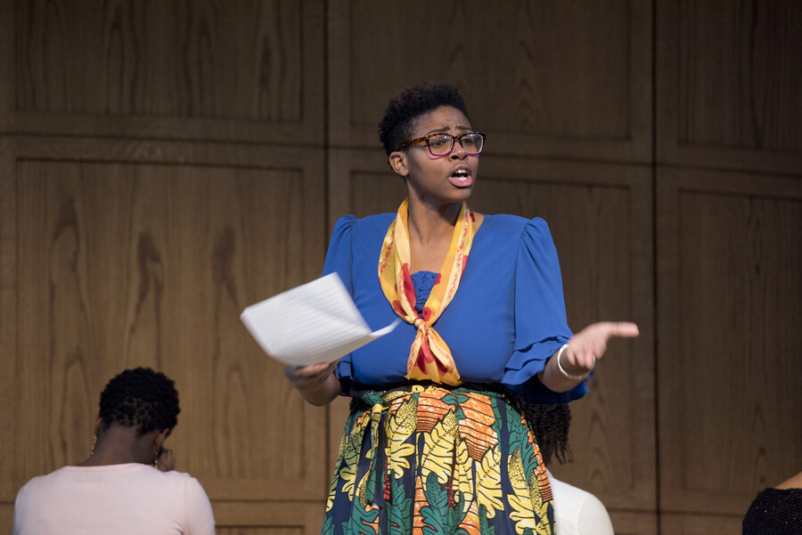 individual addressing the audience while reading aloud from a script