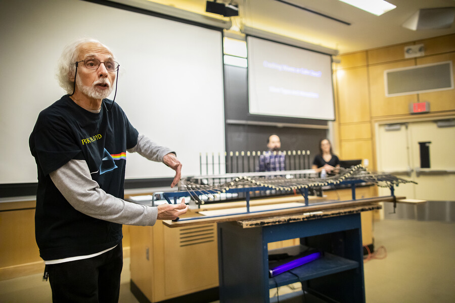 berner motions with his hands in front of a wave-generating machine as he explains a physics concept