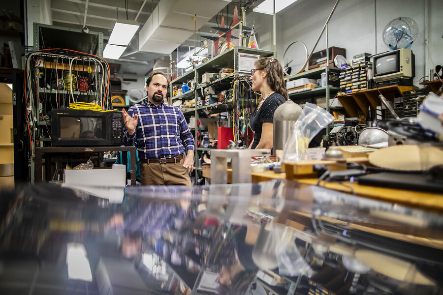 harnish and marcopul talk to each other while surrounded by equipment and tools
