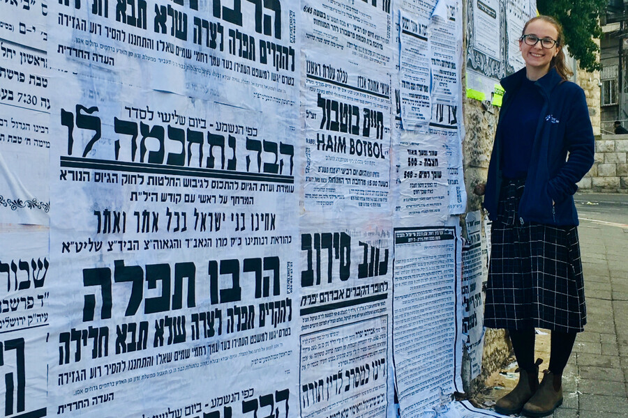 Liat Greenwood in front of a wall of pashkevilim