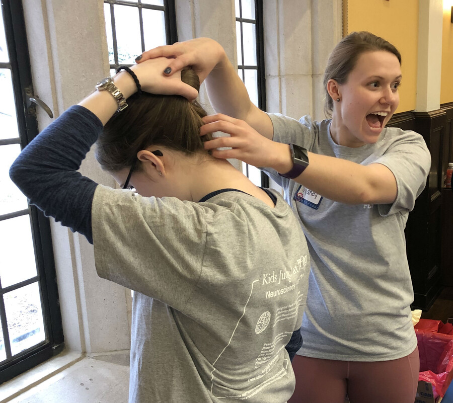 Graduate student demonstrating where the brain stem is on another graduate student