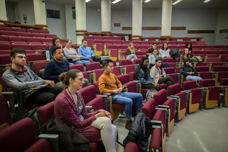People sitting in rows of red chairs in an auditorium. 