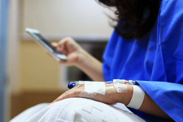 person with IV holding a cellphone