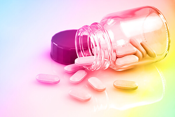 Jar of pills on its side with handful of pills spilling out.