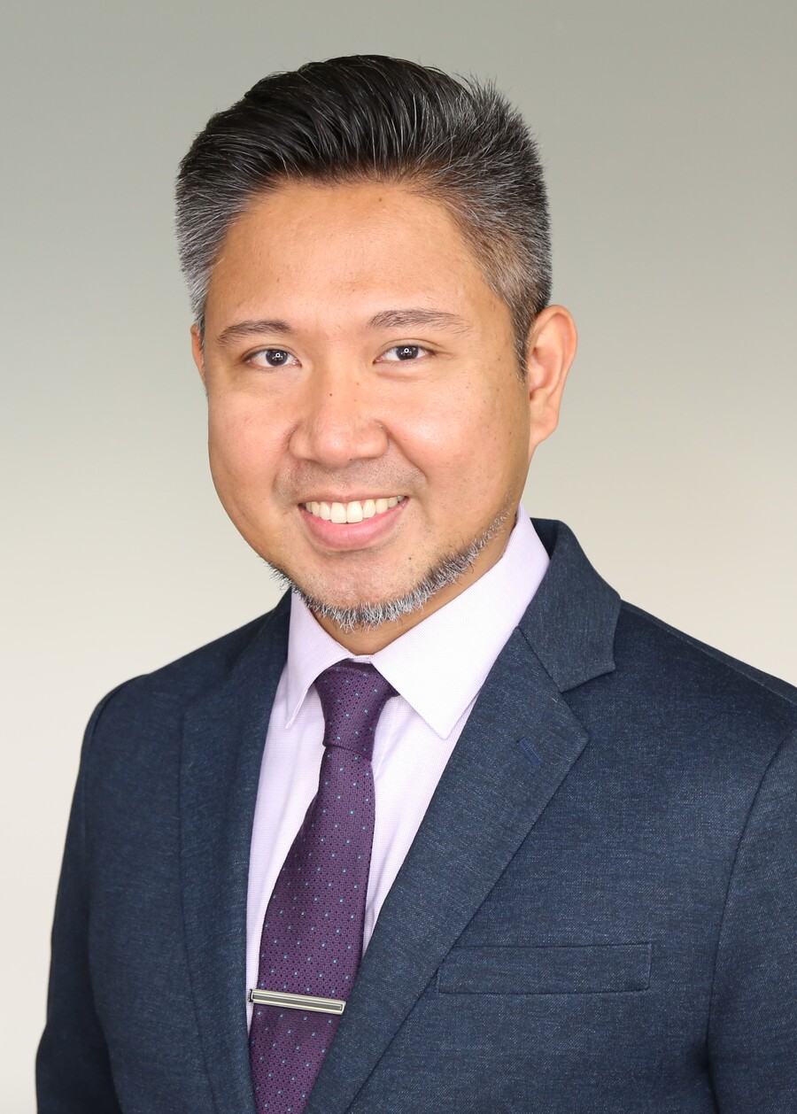  A portrait of a person in a suit wearing a purple tie. 