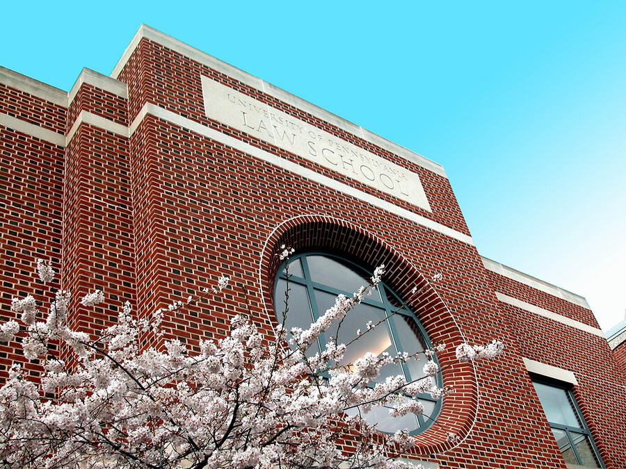Brick facade of law school building with blue sky and cherry blossoms.